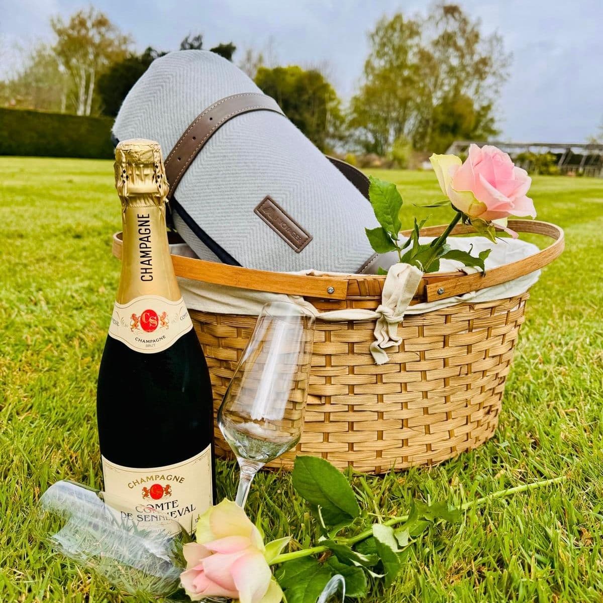 Picnic basket with sparkling wine and flowers on the lawn at Knowle Grange
